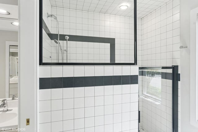 bathroom featuring a tile shower, recessed lighting, and a sink