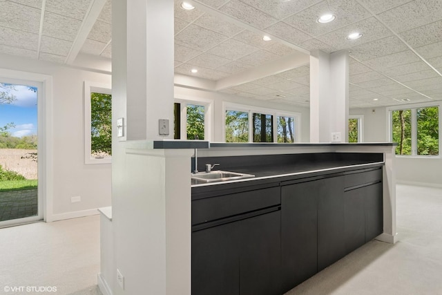 kitchen with baseboards, recessed lighting, dark cabinets, a drop ceiling, and light colored carpet