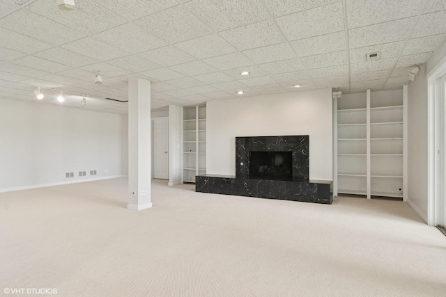 below grade area featuring carpet flooring, baseboards, a premium fireplace, recessed lighting, and built in shelves