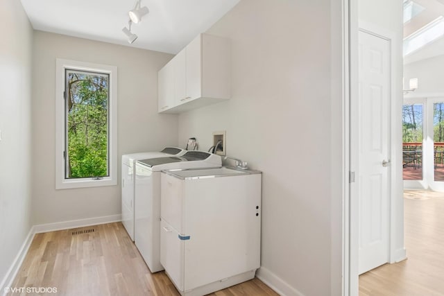 laundry area featuring cabinet space, light wood-type flooring, washing machine and dryer, baseboards, and rail lighting