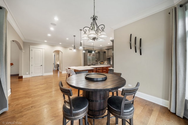 dining space featuring arched walkways, crown molding, light wood-style flooring, and recessed lighting