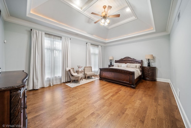 bedroom with crown molding, a raised ceiling, visible vents, and wood finished floors