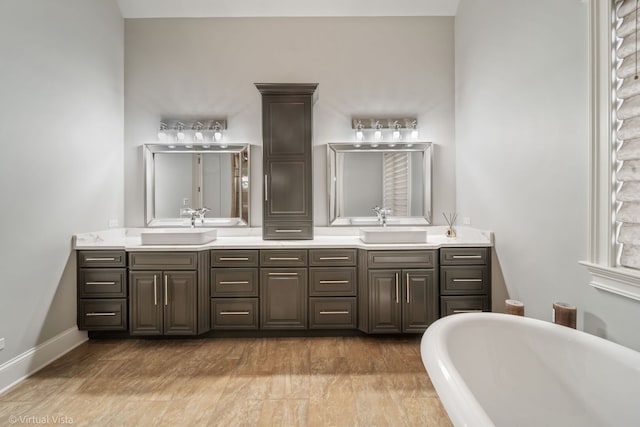 bathroom with double vanity, a freestanding bath, and a sink