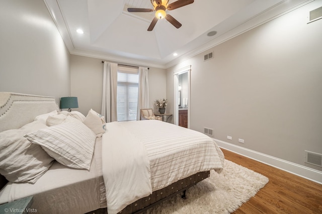 bedroom with visible vents, wood finished floors, and a raised ceiling