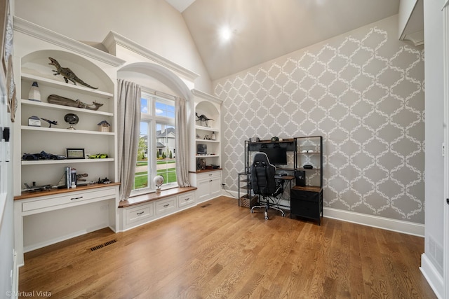 office featuring baseboards, visible vents, built in study area, high vaulted ceiling, and light wood-style floors