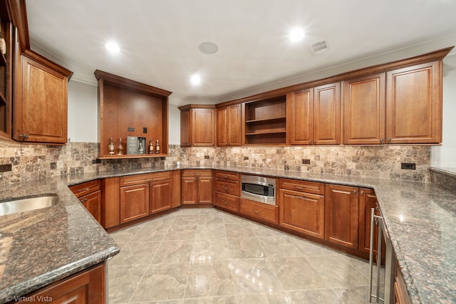 kitchen with open shelves, visible vents, stainless steel microwave, and brown cabinets