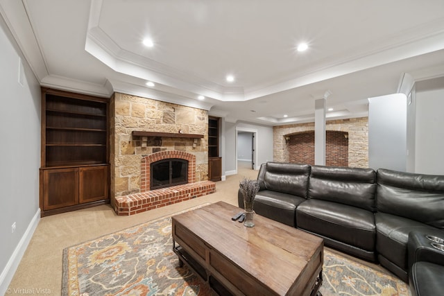 living room featuring a large fireplace, a raised ceiling, ornamental molding, and recessed lighting