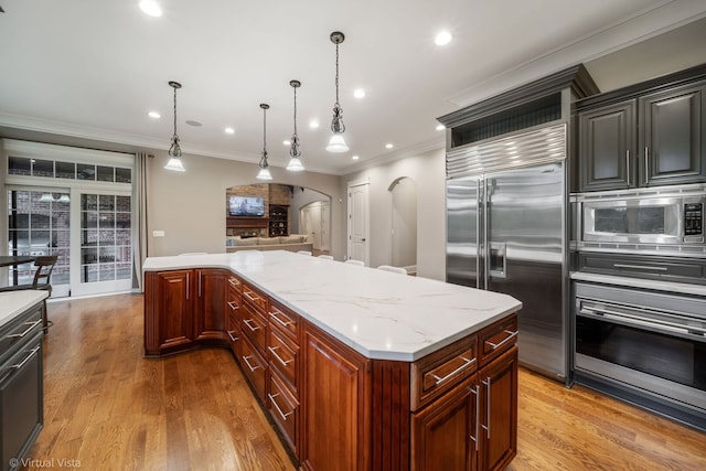 kitchen featuring arched walkways, light wood-style floors, ornamental molding, and built in appliances