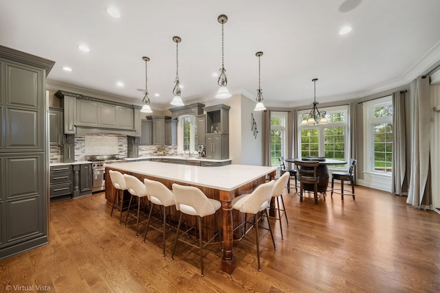 kitchen featuring ornamental molding, high end stove, light countertops, a center island, and gray cabinetry
