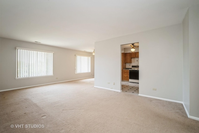 unfurnished room featuring a ceiling fan, light carpet, and baseboards