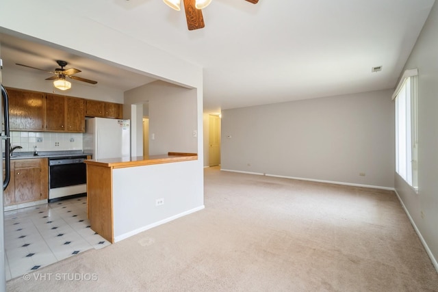 kitchen featuring dishwasher, ceiling fan, freestanding refrigerator, and brown cabinets
