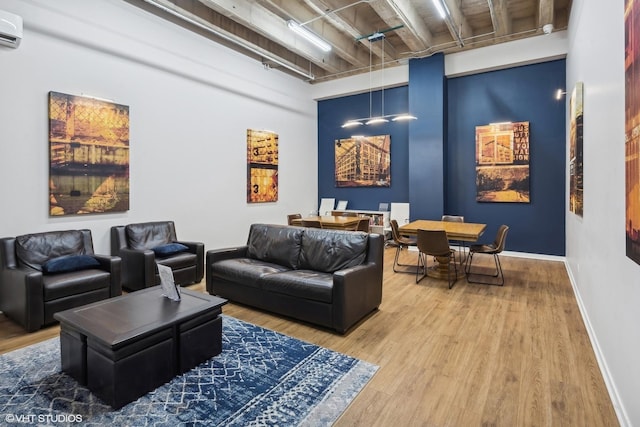 living area featuring baseboards, a wall unit AC, and wood finished floors