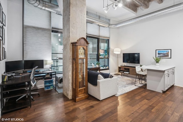 office space featuring track lighting, dark wood-type flooring, and a high ceiling