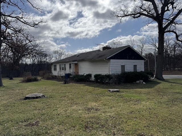 view of side of property featuring a chimney and a lawn