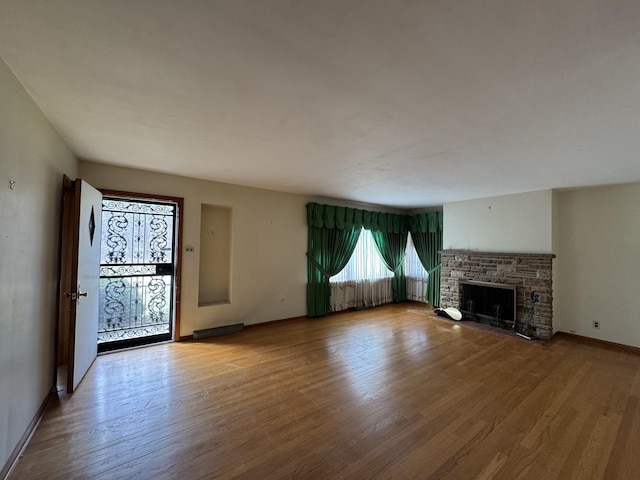 unfurnished living room with baseboards, wood finished floors, and a fireplace