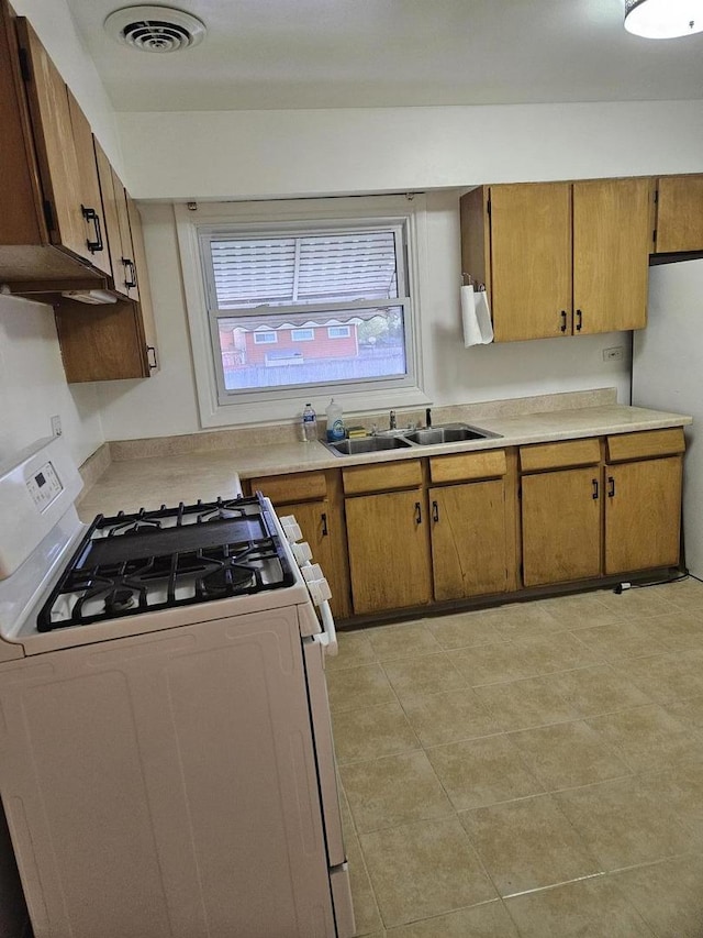 7202 W Crain St, Niles, IL 60714 - kitchen featuring brown cabinetry, visible vents, a sink, light countertops, and white range with gas cooktop