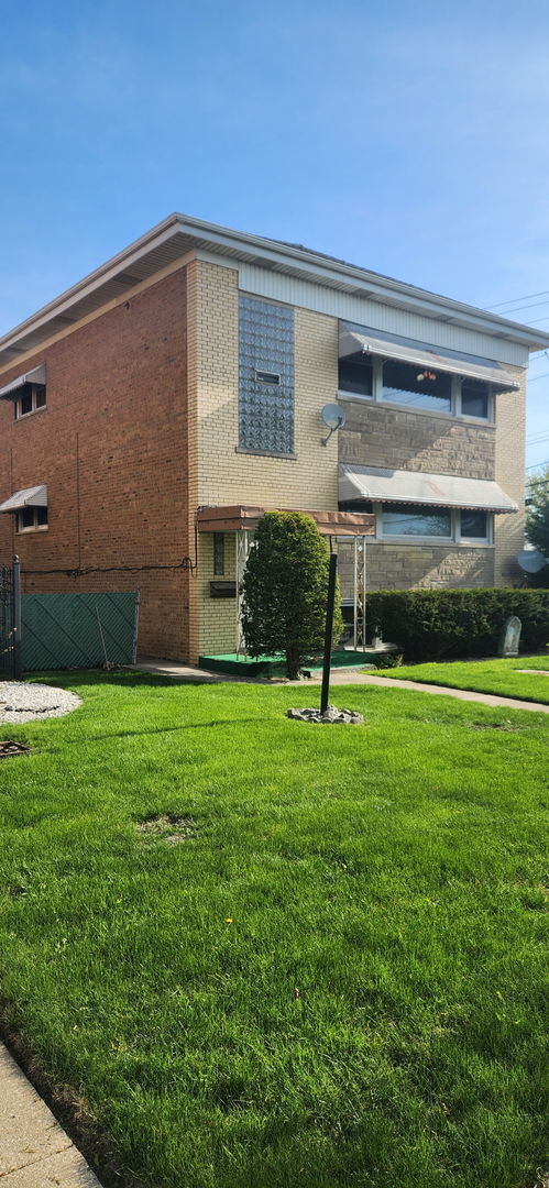 7202 W Crain St, Niles, IL 60714 - exterior space with fence, brick siding, and a front yard