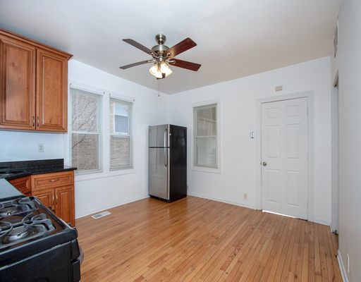 kitchen with freestanding refrigerator, black range with gas cooktop, ceiling fan, and brown cabinetry