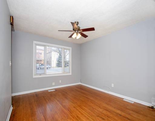 empty room with baseboards, wood finished floors, a ceiling fan, and visible vents