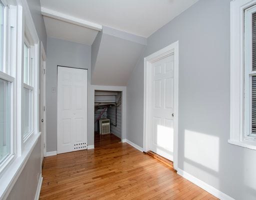 unfurnished bedroom featuring a fireplace, light wood finished floors, baseboards, and multiple windows