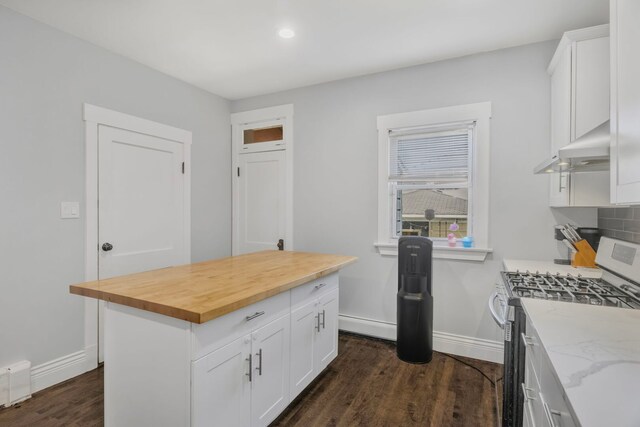 kitchen featuring stainless steel gas range oven, butcher block counters, under cabinet range hood, dark wood-style flooring, and white cabinets