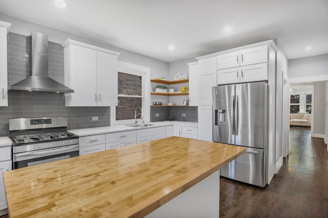 kitchen featuring a sink, white cabinetry, wall chimney exhaust hood, appliances with stainless steel finishes, and dark wood-style floors