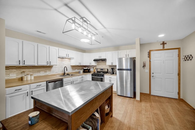 100 N Bokelman St Unit 430, Roselle, IL 60172 - kitchen featuring stainless steel appliances, a sink, under cabinet range hood, tasteful backsplash, and white cabinetry