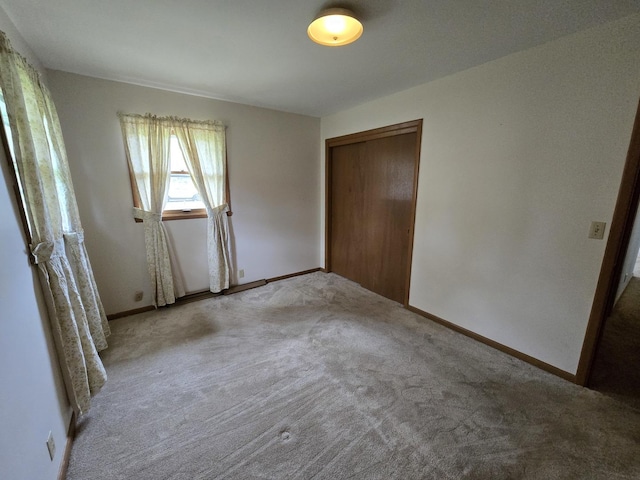 unfurnished bedroom with carpet floors, a closet, and baseboards