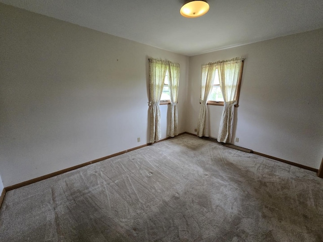 empty room featuring carpet flooring and baseboards
