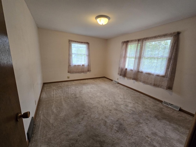 empty room featuring visible vents, baseboards, and carpet floors