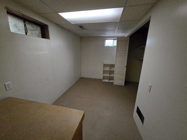 below grade area featuring carpet, a drop ceiling, and visible vents