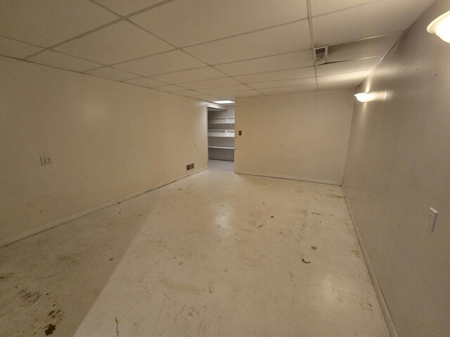 finished basement featuring visible vents, baseboards, and a paneled ceiling