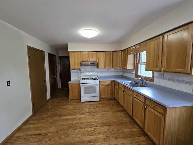 kitchen with wood finished floors, a sink, white gas range, backsplash, and under cabinet range hood