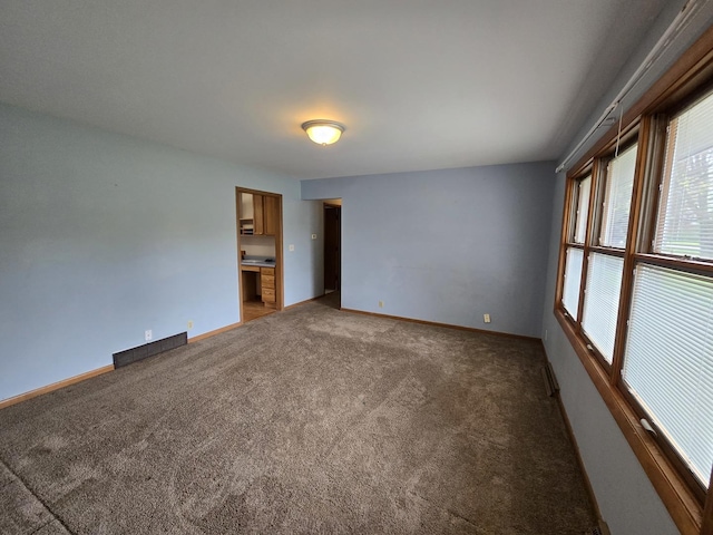 spare room featuring light colored carpet and baseboards