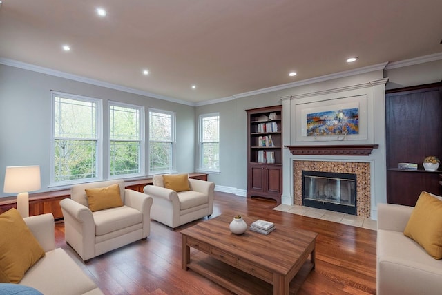 living room with wood finished floors, a fireplace, recessed lighting, ornamental molding, and baseboards