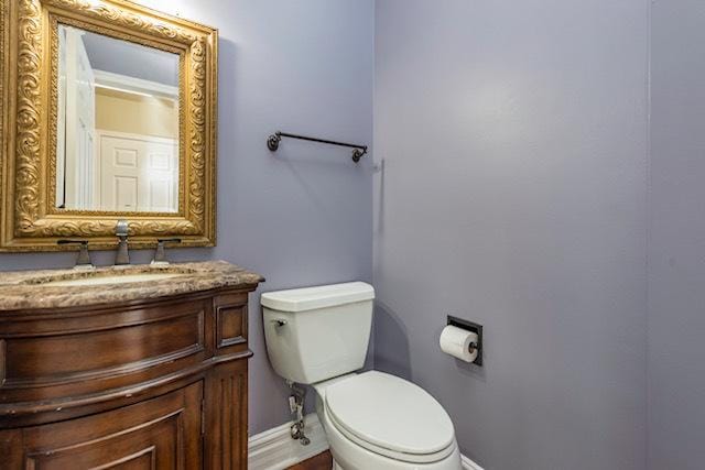 bathroom featuring baseboards, toilet, and vanity