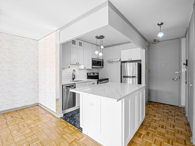 100 E Walton St Unit 18G, Chicago, IL 60611 - kitchen with appliances with stainless steel finishes, a sink, white cabinetry, light stone counters, and decorative light fixtures