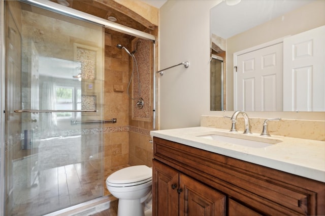 bathroom featuring toilet, a shower stall, and vanity