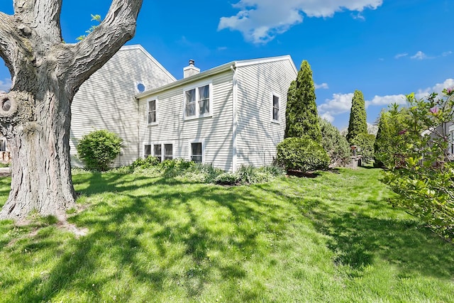 view of side of property featuring a chimney and a lawn