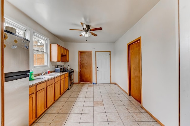 kitchen featuring a sink, light countertops, a ceiling fan, baseboards, and appliances with stainless steel finishes