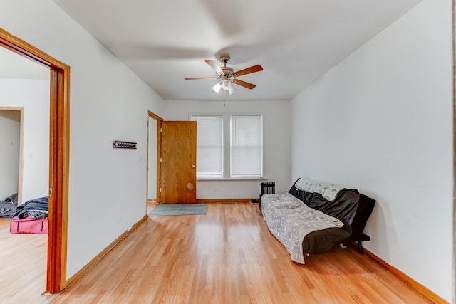 living area with ceiling fan, light wood-style flooring, baseboards, and radiator heating unit