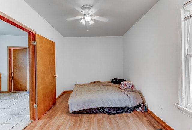 bedroom featuring a ceiling fan, light wood-style flooring, and baseboards