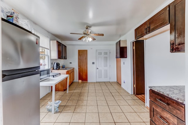 kitchen with light tile patterned floors, ceiling fan, a sink, light countertops, and appliances with stainless steel finishes