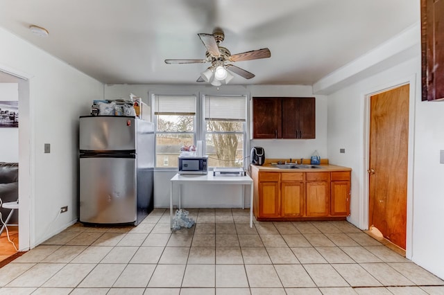 kitchen featuring light tile patterned floors, a sink, stainless steel appliances, ceiling fan, and light countertops