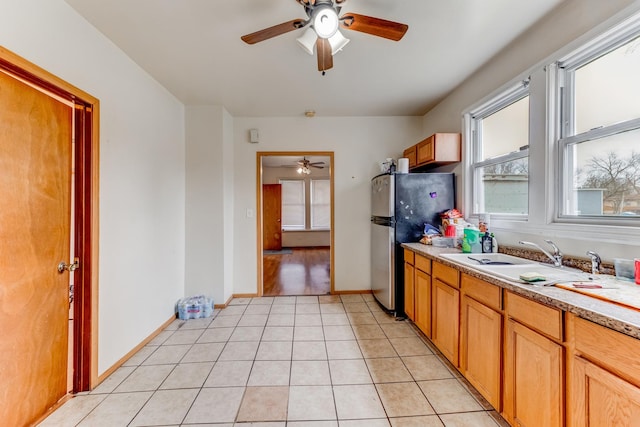 kitchen featuring a ceiling fan, a sink, freestanding refrigerator, baseboards, and light countertops