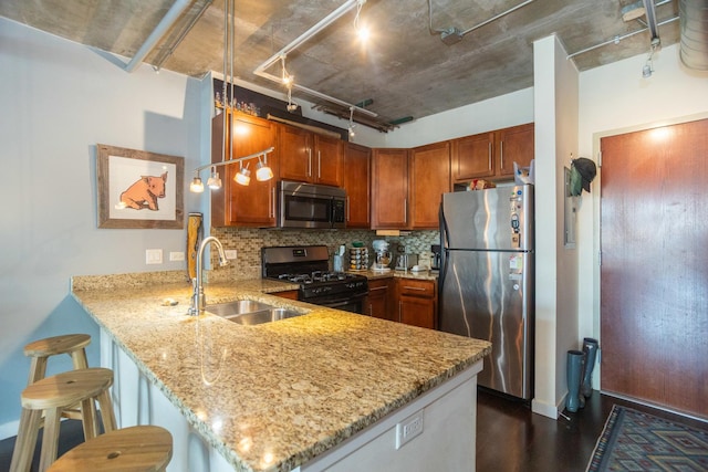 kitchen with stainless steel appliances, a sink, a peninsula, decorative backsplash, and light stone countertops