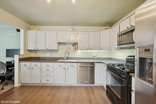 2404 Meadow Dr, Rolling Meadows, IL 60008 - kitchen featuring appliances with stainless steel finishes, a sink, white cabinets, light wood-type flooring, and dark countertops