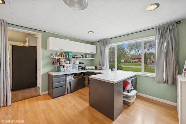 2404 Meadow Dr, Rolling Meadows, IL 60008 - kitchen with freestanding refrigerator, light countertops, light wood finished floors, white cabinetry, and a peninsula
