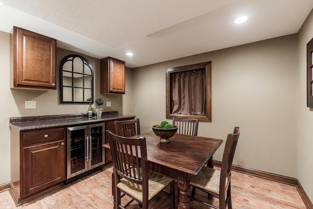 dining area featuring beverage cooler, a bar, light wood-type flooring, recessed lighting, and baseboards