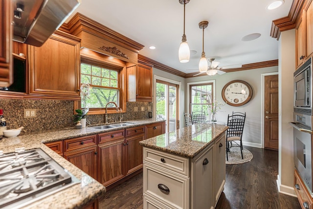 kitchen with a sink, stainless steel appliances, a ceiling fan, backsplash, and pendant lighting